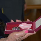 Kobiece dłonie trzymają otwarte pudełko z medalem 