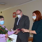 Burmistrz Marek Banaszek i kierownik USC Marzena Szczęśniak wręczają medal, kwiaty i dyplom małżonce