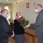 Burmistrz marek Banaszek wręcza kwiaty jubilatce. Obok stoi jej mąż.