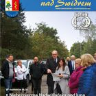 Burmistrz Marek Banaszek i radna wojewódzka Anna Brzezińska stoją na tle autobusu i oglądają plany. Wokół nich stoją mieszkańcy.