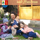 Mama z trójką dzieci siedzą w kurtkach na trawie.
