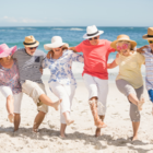 Grupa seniorów pozuje do zdjęcia na plaży.