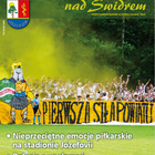 Grupa kibiców na boisku przed napisem 