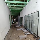 Budowa Miejskiego Przedszkola nr 1 - na fotografii widoczne wnętrze budynku, ściany szkieletowe, belki stropowe zielone, pod ścianą ustawiony stojak z oknami