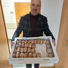 Piotr Gąszcz - Zstępca Burmistrza w Urzędzie Miasta z pudełkiem pączków oblanych lukrem, w tle drzwi z widokiem na korytarz