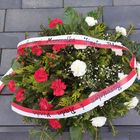 Wiązanka kwiatów biało-czerwonych z szarfą z napisem W 90. Rocznicę Śmierci Marszałka Józefa Piłsudskiego Burmistrz i Rada Miasta